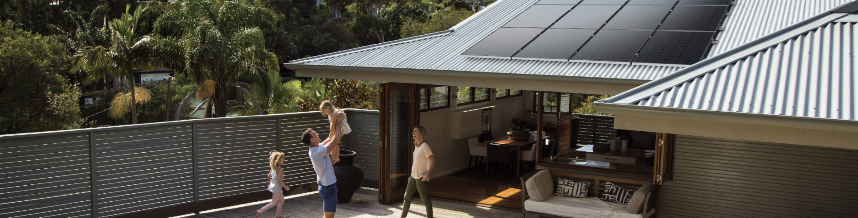 family playing in the backyard new solahart solar panels are installed on roof